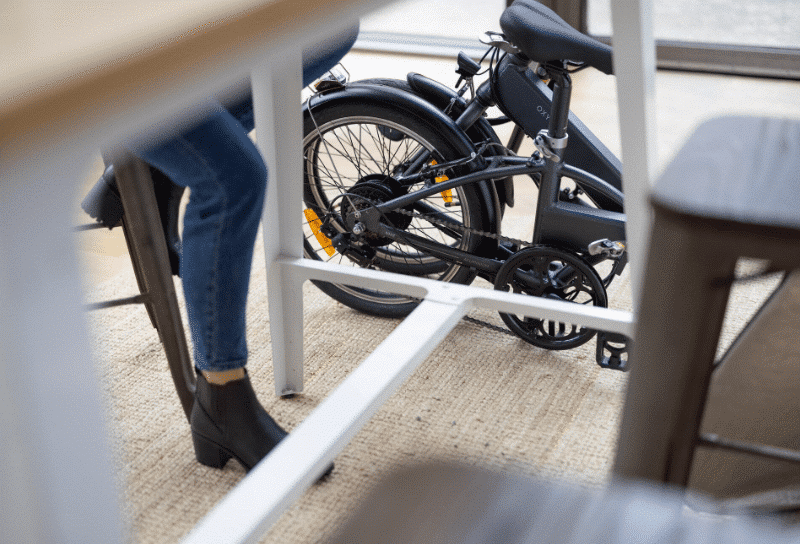 Un vélo pliant électrique (Btwin Tilt 500 E) sous un bureau