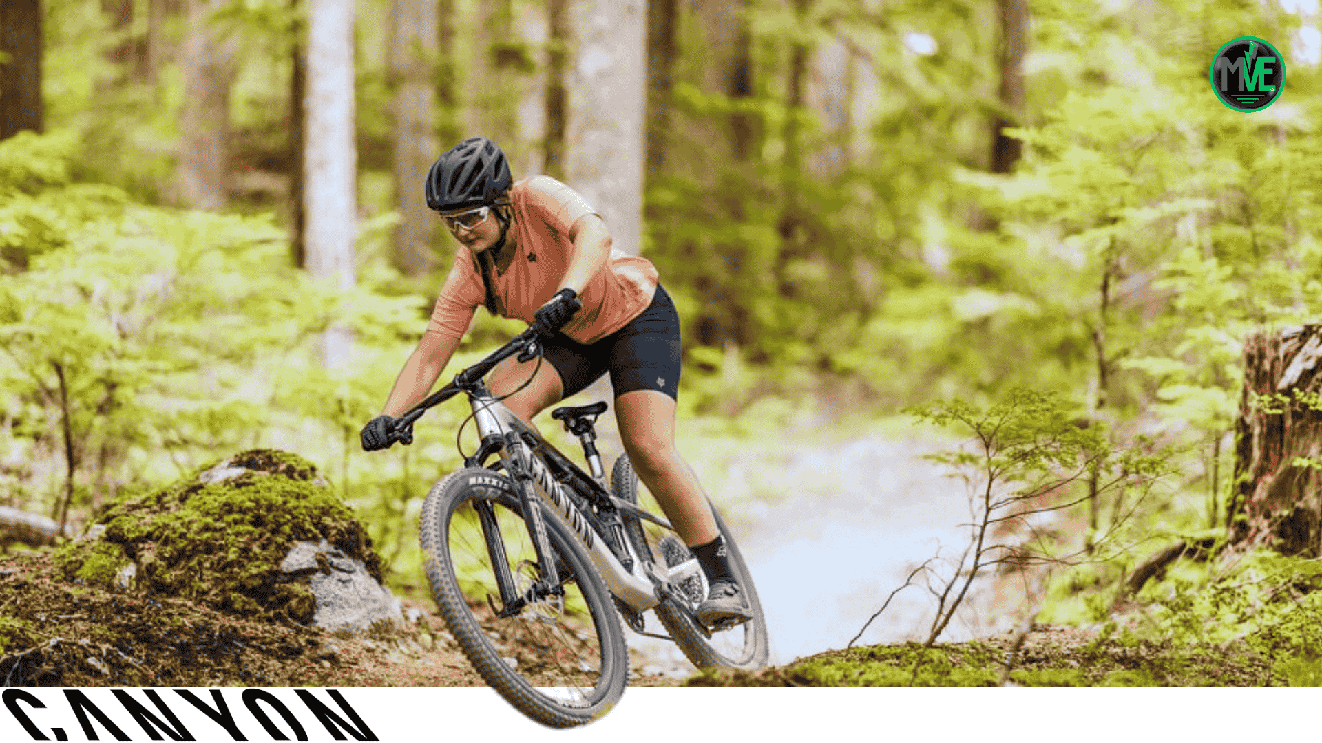 Cycliste casquée en VTT Canyon sur sentier forestier, virage serré et poussière soulevée.