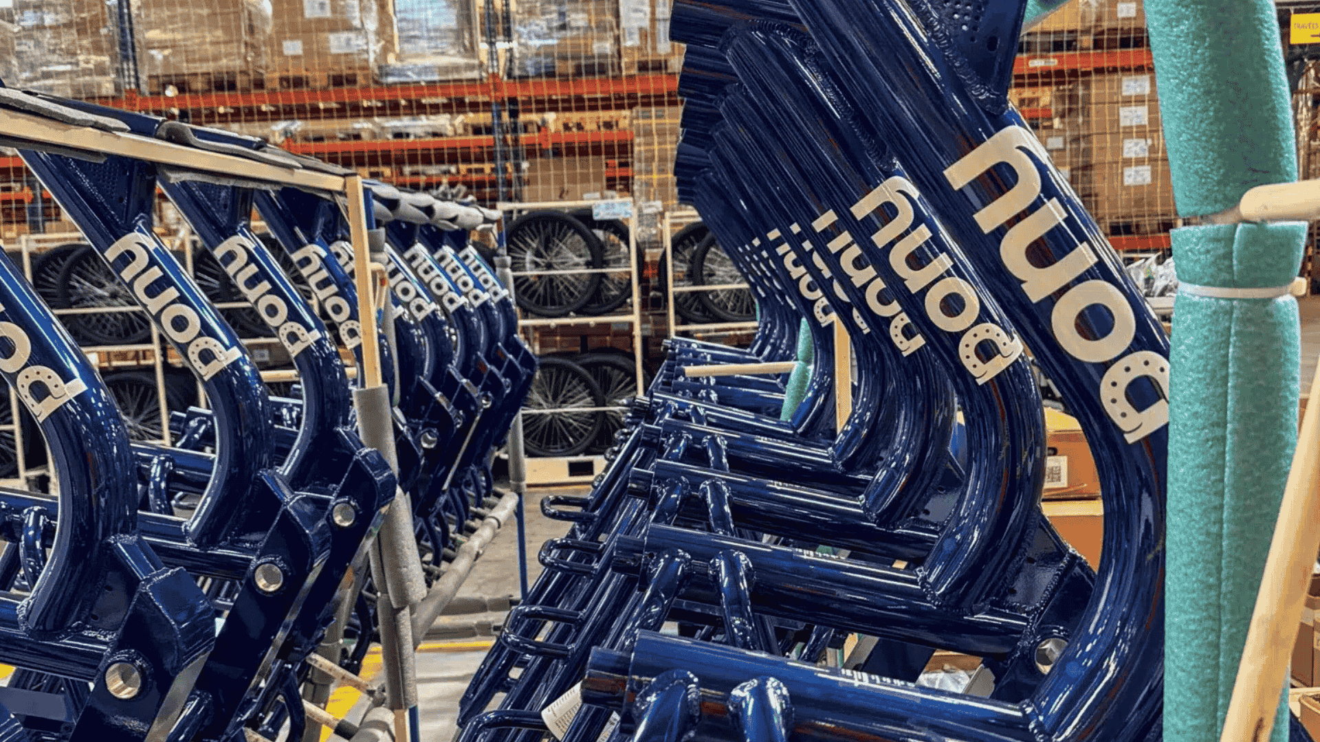 Rangée de cadres bleus de vélos électriques Double Pony entreposés avant assemblage à la Manufacture Française du Cycle