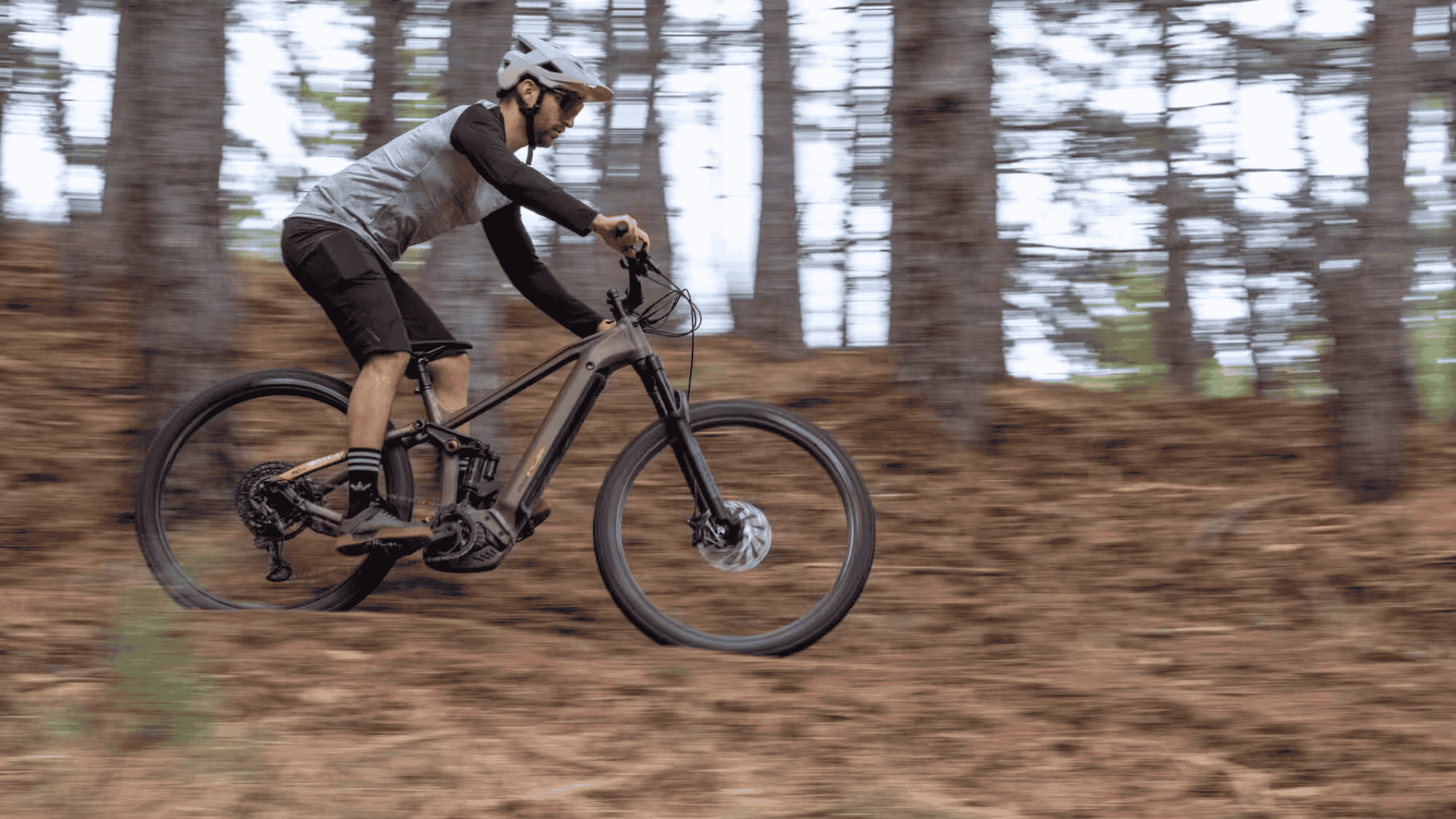 VTTiste dévalant une pente forestière sur un vélo électrique Lombardo tout-suspendu