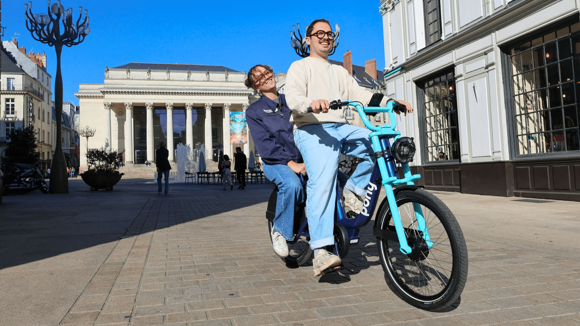 Deux personnes roulent sur un vélo électrique Double Pony de Pony dans le centre-ville de Nantes