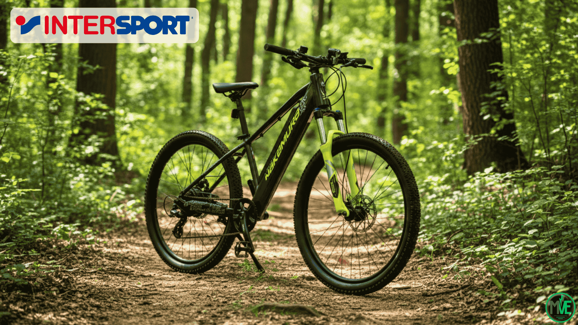 VTT électrique Nakamura E Summit EVO 26″ noir et jaune, posé sur un chemin forestier, avec fourche suspendue et freins à disque