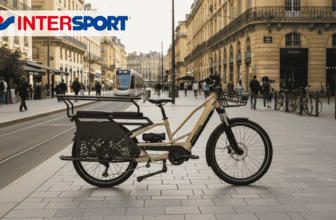 Vélo cargo électrique Nakamura Crossover Longtail en promotion chez Intersport, stationné en ville sur une piste cyclable