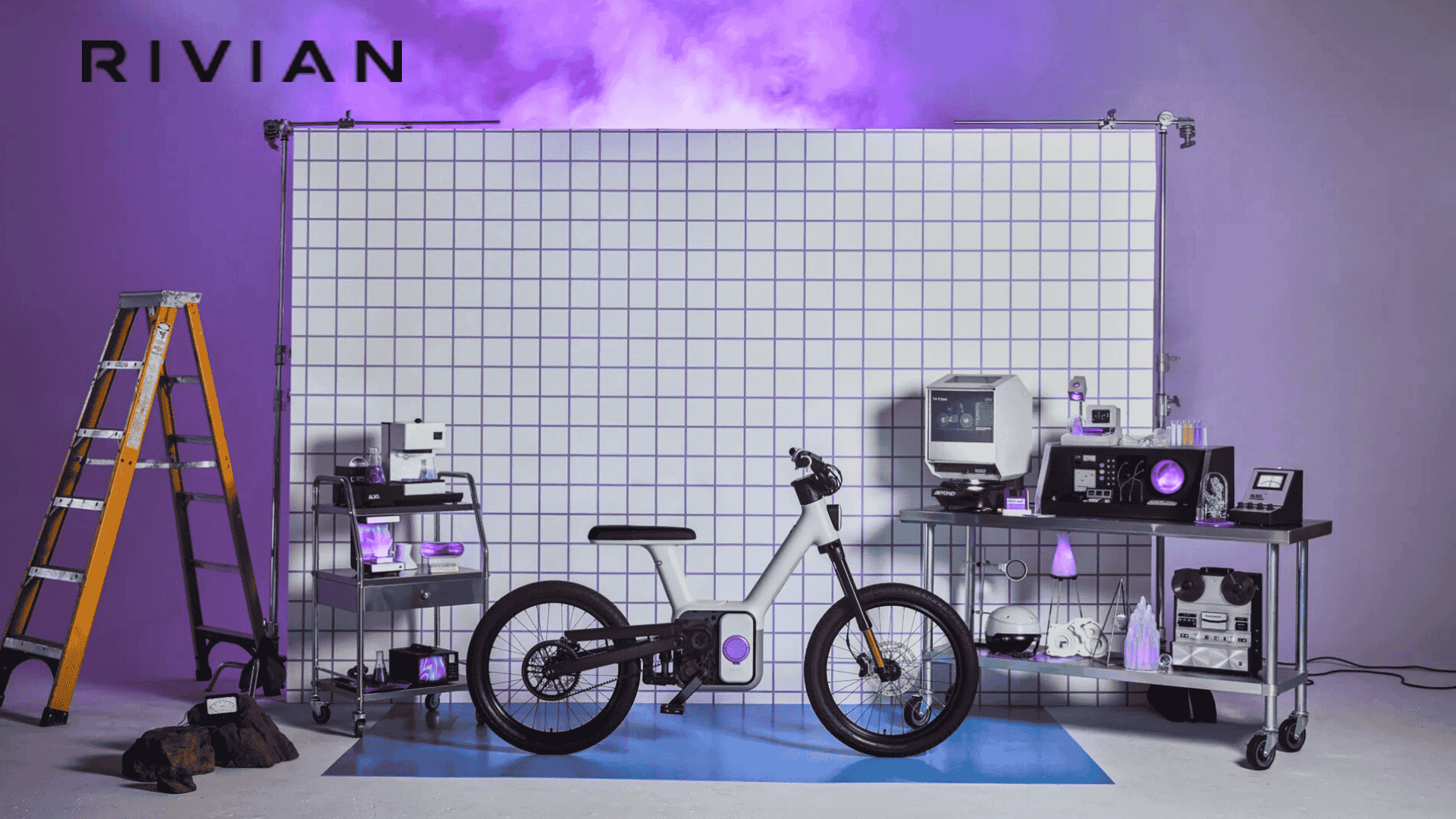 Vélo électrique Also TM-B de Rivian en studio violet : cadre modulaire, bloc moteur-batterie central, écran circulaire et transmission by-wire
