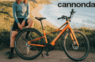 Cannondale FlyingV orange, vélo de ville électrique tout carbone avec courroie Gates et moteur Bosch SX, photographié face à l’océan