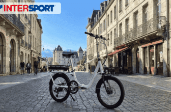 Vélo électrique pliant Nakamura E-Flex 2.0 en ville devant une place historique, promotion Intersport
